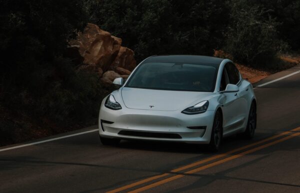 White tesla drives on a highway.