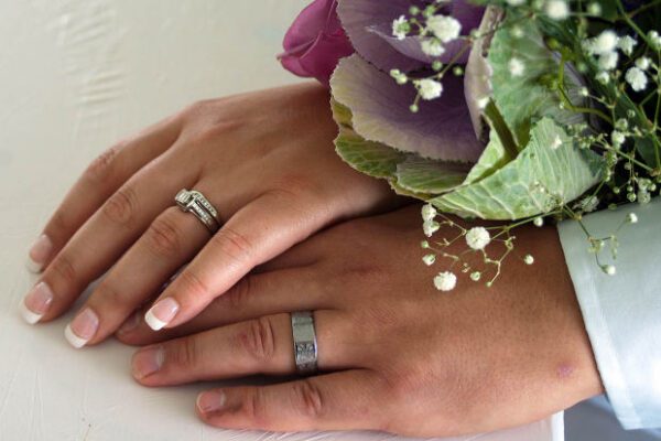 Two hands of a married couple with wedding bands on their wedding day.