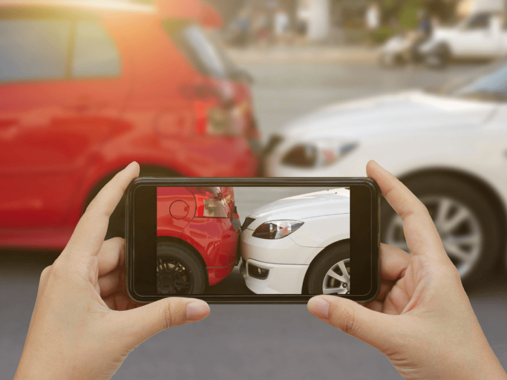 Someone taking a photo of a car crash on their smartphone.