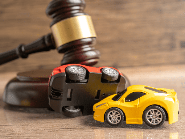 Two toy cars in a pile-up in front of a judges gavel.